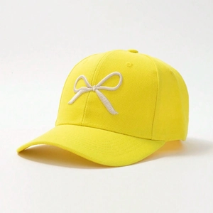 Detail shot of a yellow cotton baseball cap with white 3D embroidered bow on side profile