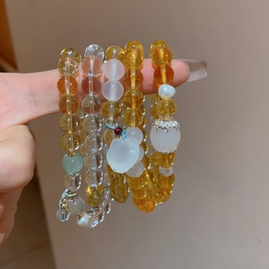 Detail of beaded bracelets featuring yellow citrine, white chalcedony, and a gourd charm