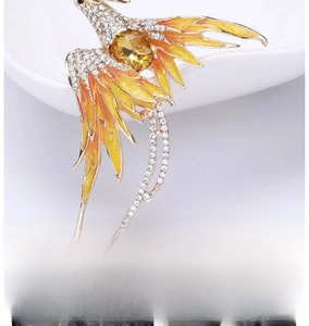 Macro view of phoenix brooch featuring yellow gemstone and colorful enamel details