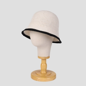 Detail of elegant knitted bucket hat with chic black wavy trim on beige fabric texture
