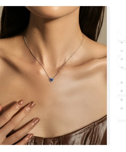 Close-up of heart-shaped blue sapphire pendant necklace with diamond halo on neck