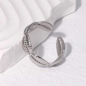 Detailed view of silver titanium steel ring with leaf textures on a white stone pedestal