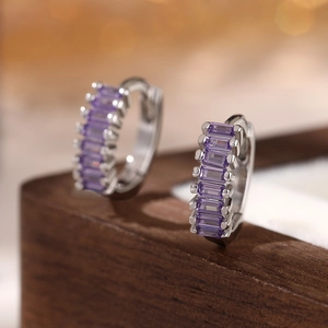 Macro shot of silver 925 hoop earrings featuring purple emerald-cut cubic zirconia stones
