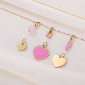 Detail of a gold necklace featuring a pink heart enamel pendant and small gold heart charms