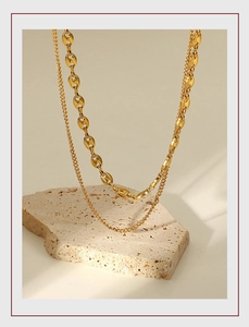 Detail view of 18K gold plated double layer pig nose link necklace on travertine stone