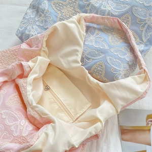 Detail showing the inner zipper pocket and butterfly embroidery on the pink silk tote bag