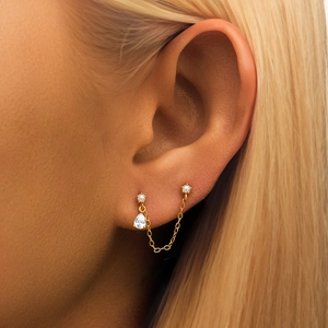 Macro view of gold chain earrings with pearls and a crystal teardrop pendant