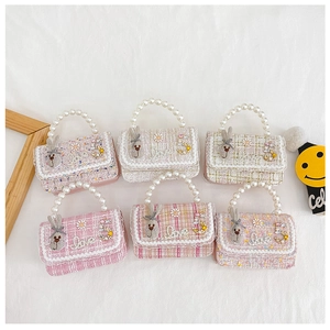 Flat lay of multiple girls tweed crossbody bags with pearl handles and bow details