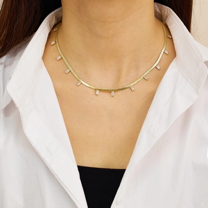 Detail of flat gold snake chain necklace featuring rectangular zircon pendants on neck