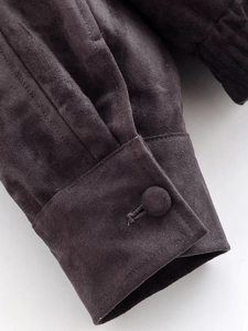 Détail de la manchette de veste en daim gris foncé montrant le bouton et les coutures