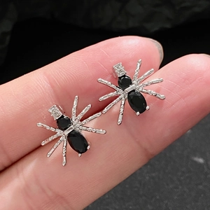 Gothic silver spider stud earrings with black gemstones and crystals on finger