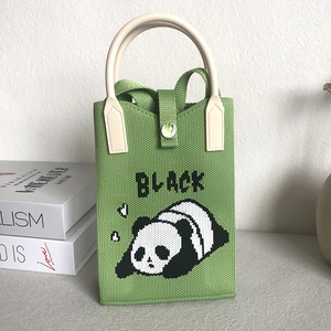 Detailed view of a green knitted panda phone bag with a cream handle and button closure