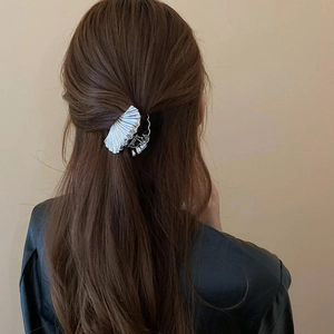 Detail view of a silver shell-textured hair claw clip styling a half-up hairstyle