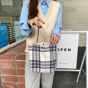 Detail of vintage plaid wool handbag with golden snap button and woven handles