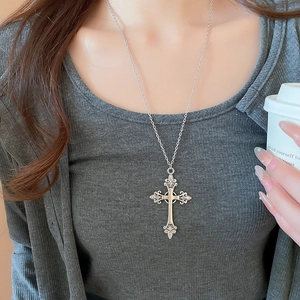Detail of silver vintage cross pendant necklace with rhinestones on female model