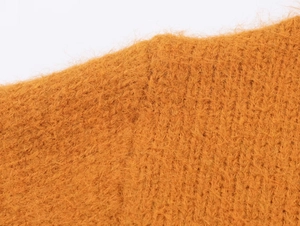 Gros plan sur la texture du tricot orange montrant des fibres douces et une maille épaisse