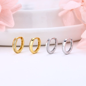 Détails macro des petites créoles en or et argent avec pavé de pierres de zircone