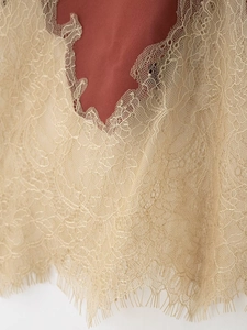 Close-up of beige floral lace trim with eyelash fringe on a satin skirt fabric