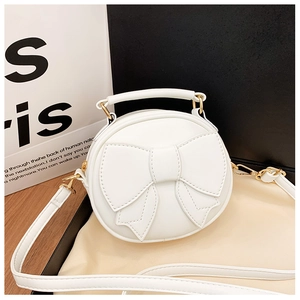 Close-up of white round children's purse featuring a 3D bow and gold metal hardware