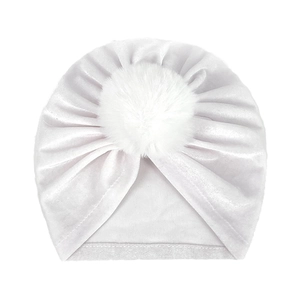 Close-up of soft white velvet baby turban hat with a plush faux fur pompom on top