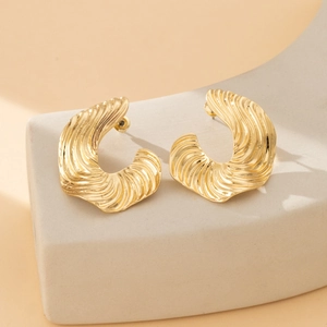French style gold irregular textured metal C-shape stud earrings on a stone base