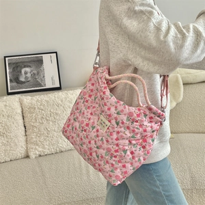 Quilted floral tote bag with pink flower pattern and adjustable shoulder strap worn by a model