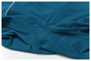 Detalle macro de mallas de yoga verde azulado con entrepierna y costuras planas