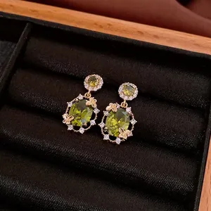 Boucles d'oreilles papillon dorées avec zircon vert olive et détails en cristal