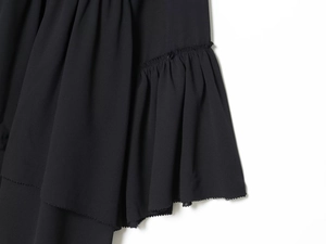 Close-up detail of black chiffon top featuring elegant ruffle trim and fine fabric texture