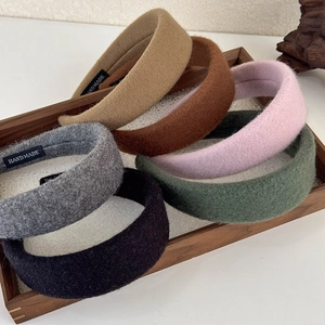 Close-up of assorted wool fabric headbands with handmade tags in a wooden tray