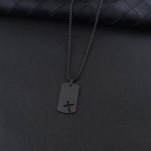 Detail shot of black dog tag pendant with hollow cross design and red gemstone accent