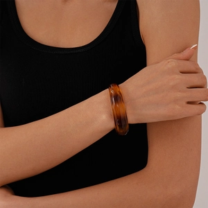 Close-up of an irregular amber acrylic bangle worn by a model with a minimalist retro vibe