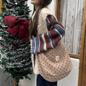 Detail of soft cream fleece shoulder bag with red heart patterns and brand label