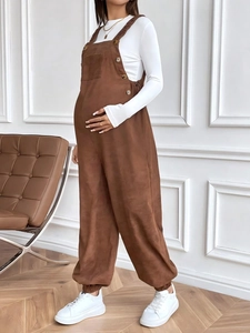 Detail view of brown corduroy maternity overalls with adjustable waist and side buttons