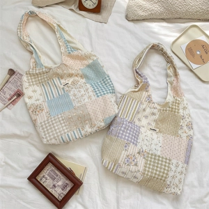 Vista piatta di borse tote patchwork con motivi floreali trapuntati blu e viola