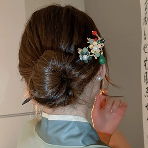 Close-up of golden floral hair pin with green beads worn in an elegant bun hairstyle