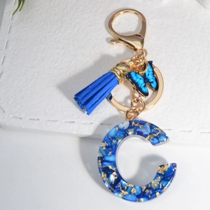 Royal blue resin letter C keychain with gold foil flakes, tassel and butterfly charm