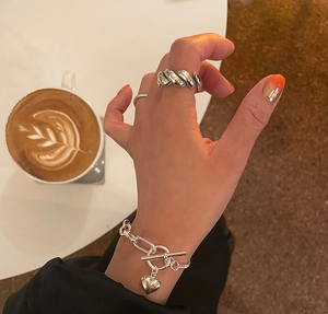 Detailed view of silver heart pendant bracelet and textured minimalist ring set