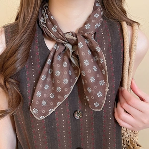 Detail of coffee brown floral silk scarf tied around neck showing smooth satin texture