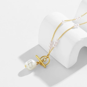 Close-up of gold chain body belt with white pearls and OT toggle clasp on geometric prop