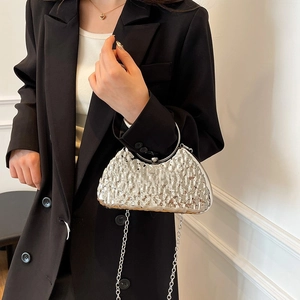 Silver evening clutch bag with pleated texture and round metal handle shown with strap