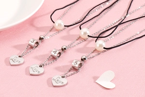 Detail of double-layer stainless steel necklaces with Love hearts and pearl accents