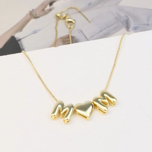 Macro detail of 18k gold plated brass MOM bubble letter pendant with fine box chain