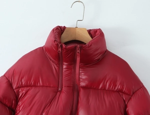 Detail of red stand-collar puffer jacket featuring double zippers and glossy quilted fabric