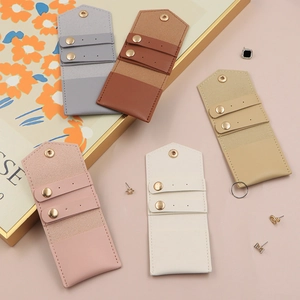 Detailed view of portable jewelry pouches in pink, white, gray, and brown soft leather