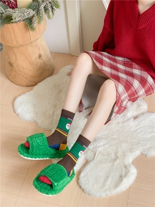 Cozy green plush slippers and festive Christmas socks with Santa Claus on a soft rug