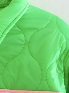 Vista macro dettagliata della cucitura trapuntata a onde su giacca di nylon verde brillante