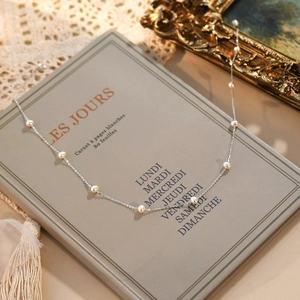 Detail of freshwater pearl necklace laid on a vintage French notebook with lace accents