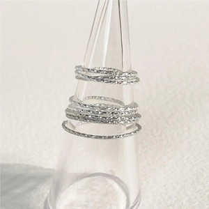 Macro detail of stacked S925 sterling silver slim rings with faceted texture on a stand