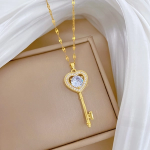 Detail of a heart-shaped key pendant necklace in gold finish with sparkling zircons